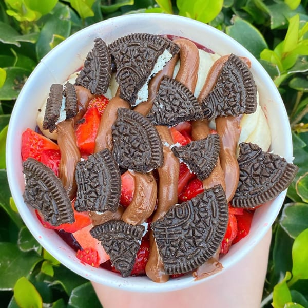 Protini Bar acai bowl with strawberries, banana, chocolate drizzle, and broken Oreo cookies.