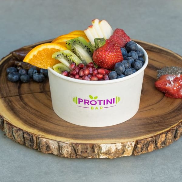 Protini Bar acai bowl with blueberries, strawberries, kiwi, orange, pomegranate, and apple slices.