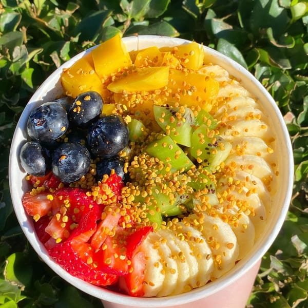 Colorful acai bowl from Protini Bar, topped with mango, blueberries, kiwi, strawberries, and bananas.