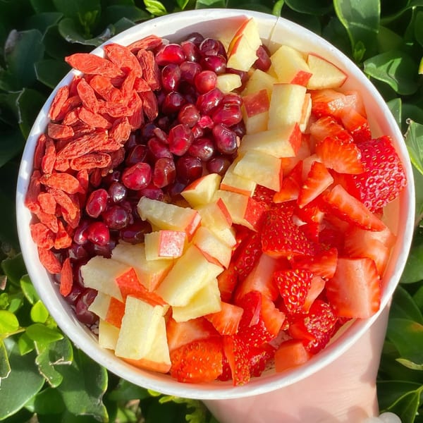 A Protini Bar acai bowl with goji berries, pomegranate, diced apples, and strawberries.